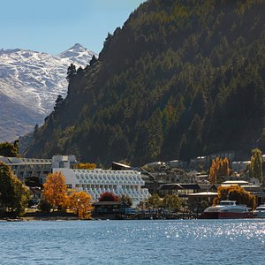 External photo of Crowne Plaza Queenstown and lake, with Cardrona Peak and ski fields on the background