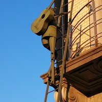 Romeo - Sculpture of a man with a guitar on his back climbing on a ladder