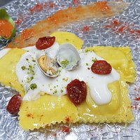 Ravioli ricciola e pistacchi con crema alle vongole e pomodorini confit