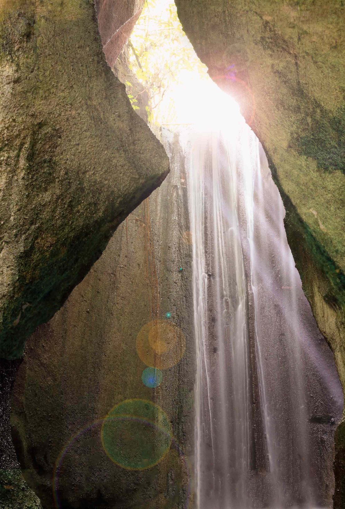 Mystical cave entrance with water flowing through rocky canyon walls