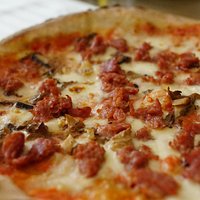 Pizza Boscaiola con salsa pomodoro, mozzarella fresca, salsiccia Italiana y champiñones.