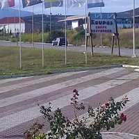 Flags and sign by the roadside - note different spelling of name