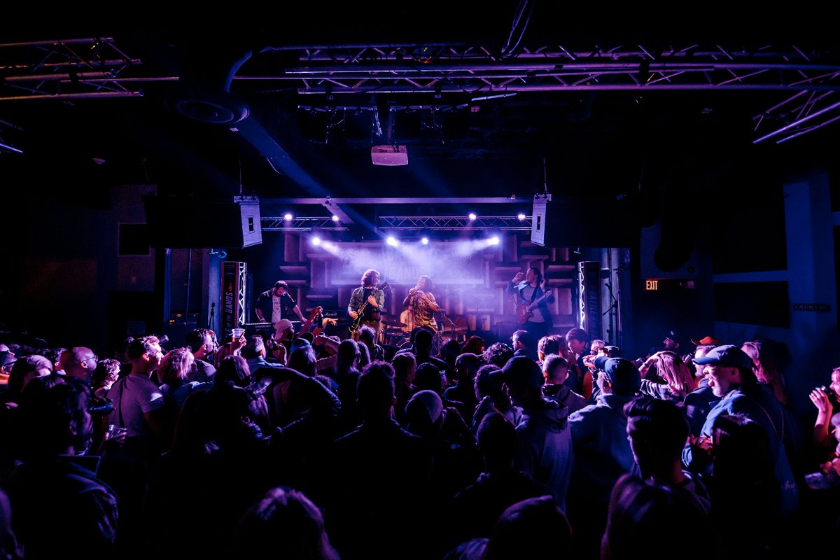 HIFI is basked in purple light with a crowd of people eager to hear the performer on the stage.