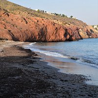 Red rocks reflected in the wet sand at Playa Cueva de Lobos
