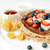 Weekend Brunch -- Golden Pancakes cooked to perfection topped off with fresh fruit, maple syrup, and our homemade cashew cream.