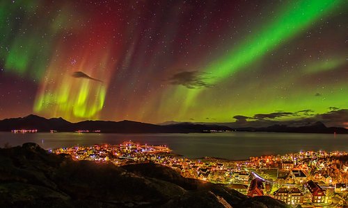 et bilde over Lødingen med nordlys over hele byen. bilde er tatt fra en liten topp rett bak hotellet. det er ca. 10 gå avstand