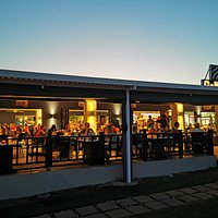 Open restaurant filled with people and a nice atmosphere.It has a lawn for the kids to play whilst having your meal and 30m from the beach.