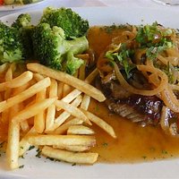 Beefsteak avec oignons et sauce au vin accompagné de frites et brocolis.
