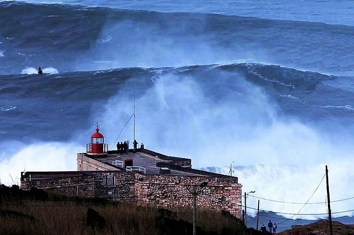 close up of traditional vintage wooden fishing boat on main beach of  village of Nazare.The high cliff of Nazare Sitio and its lighthouse on  background. Nazare, in Portugal Stock Photo