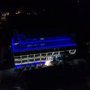 Nachtaufnahme von der Seeseite zum Hotel mit beleuchtetem Glasgeländer.