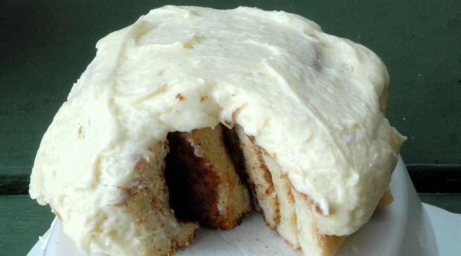 This cinnamon bun  with brown sugar and cinnamon swirls is topped with a generous scoop of delicious cream cheese icing.