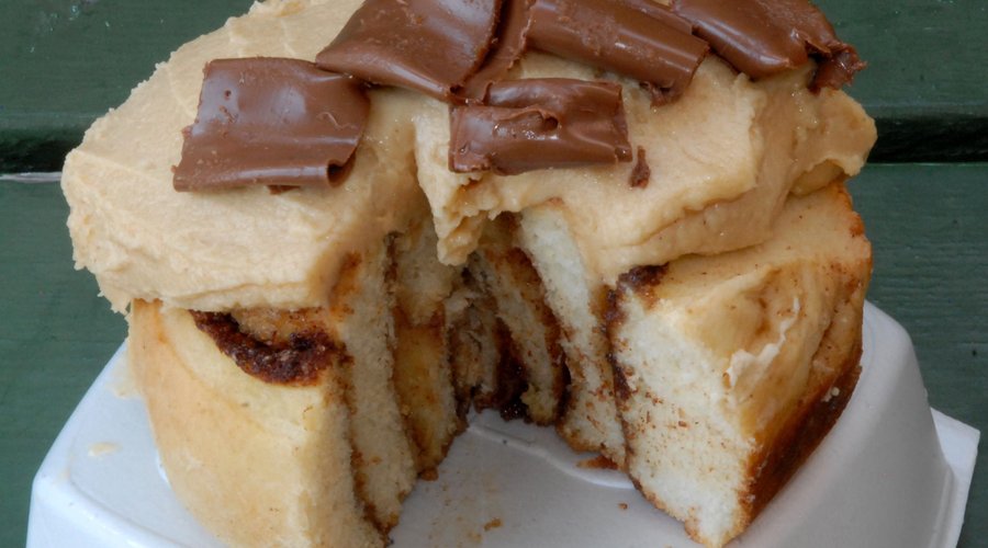 A cinnamon bun with brown sugar and cinnamon swirls topped with peanut butter icing with or without chocolate curls.
