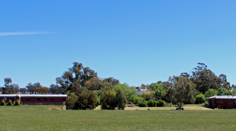 Panoramic view of the Overlander train carriage and the City Circle train carriage with the homestead in the background