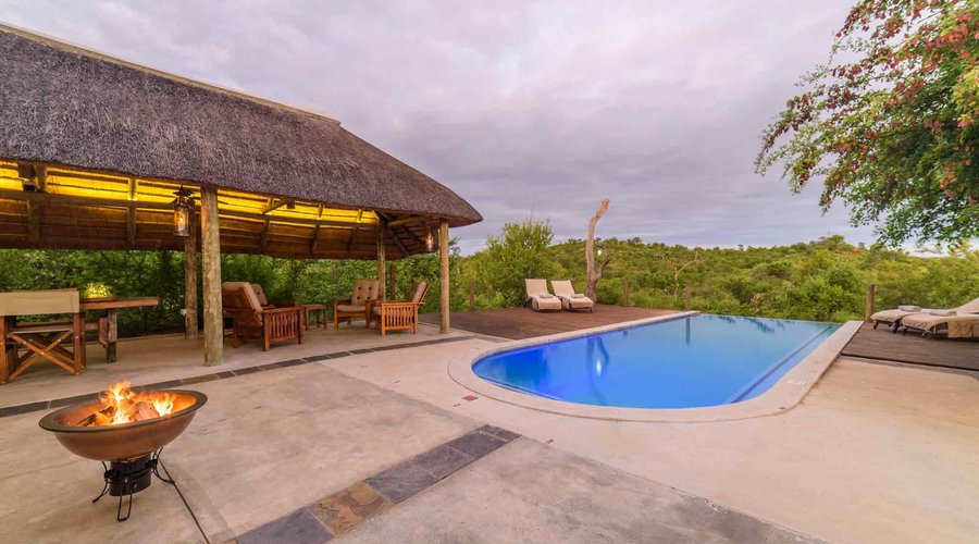Lengau Lodge - infinity pool with sundecks and sun loungers with alarge shaded area with a thatch roof. The pool has a length of 11 meter and a depth of 1.65 meter, which allows you to actually have a real swim