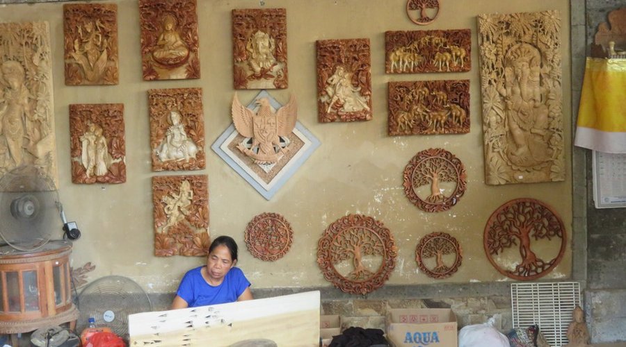 Artisan working on wood panel with finished works on display