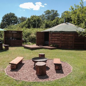 Woodpecker Yurt with fire pit area in the foreground and camp kitchen in the background