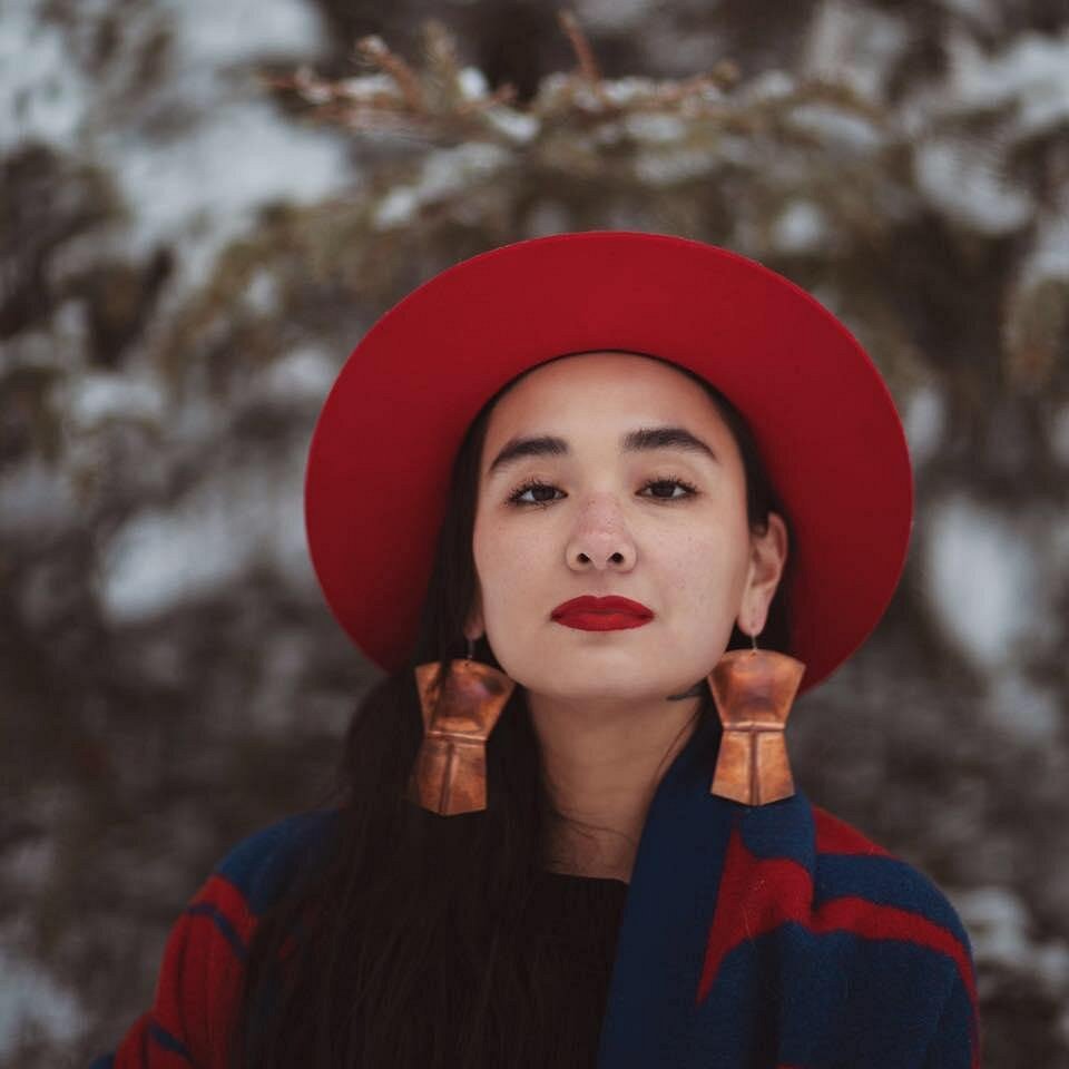 Maka Monture Päki in a red hat and big copper earrings
