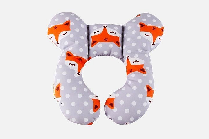 A neck pillow for babies. It is purple in color and has white polka dots. It features several playful illustrations of a sleeping fox.