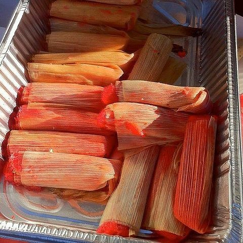 A stack of tamales in a metal tray.