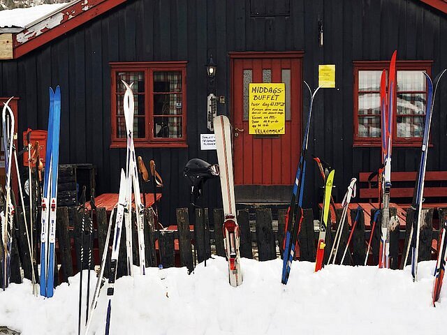 A person in bright yellow and red ski clothes by a ski lift.