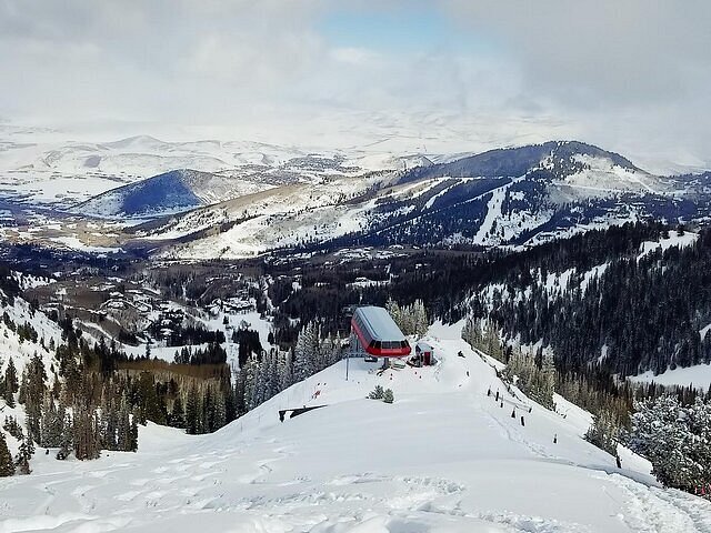 Two masked people riding a ski lift.