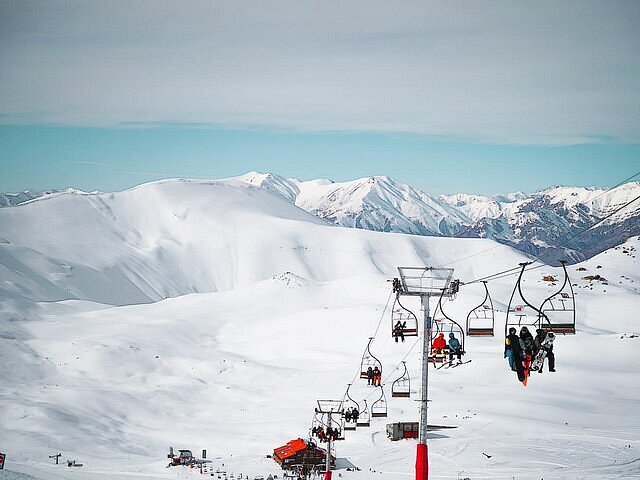 An adult holding up a kid on skis.
