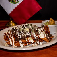 Crujientes nachitos de maíz bañados en una deliciosa salsa roja de chile guajillo, cebollita, cilantro picado, guacamole, crema agria y acompañados de frijoles refritos. Pídelos de carne asada a la parrilla o pollo desmenuzado.