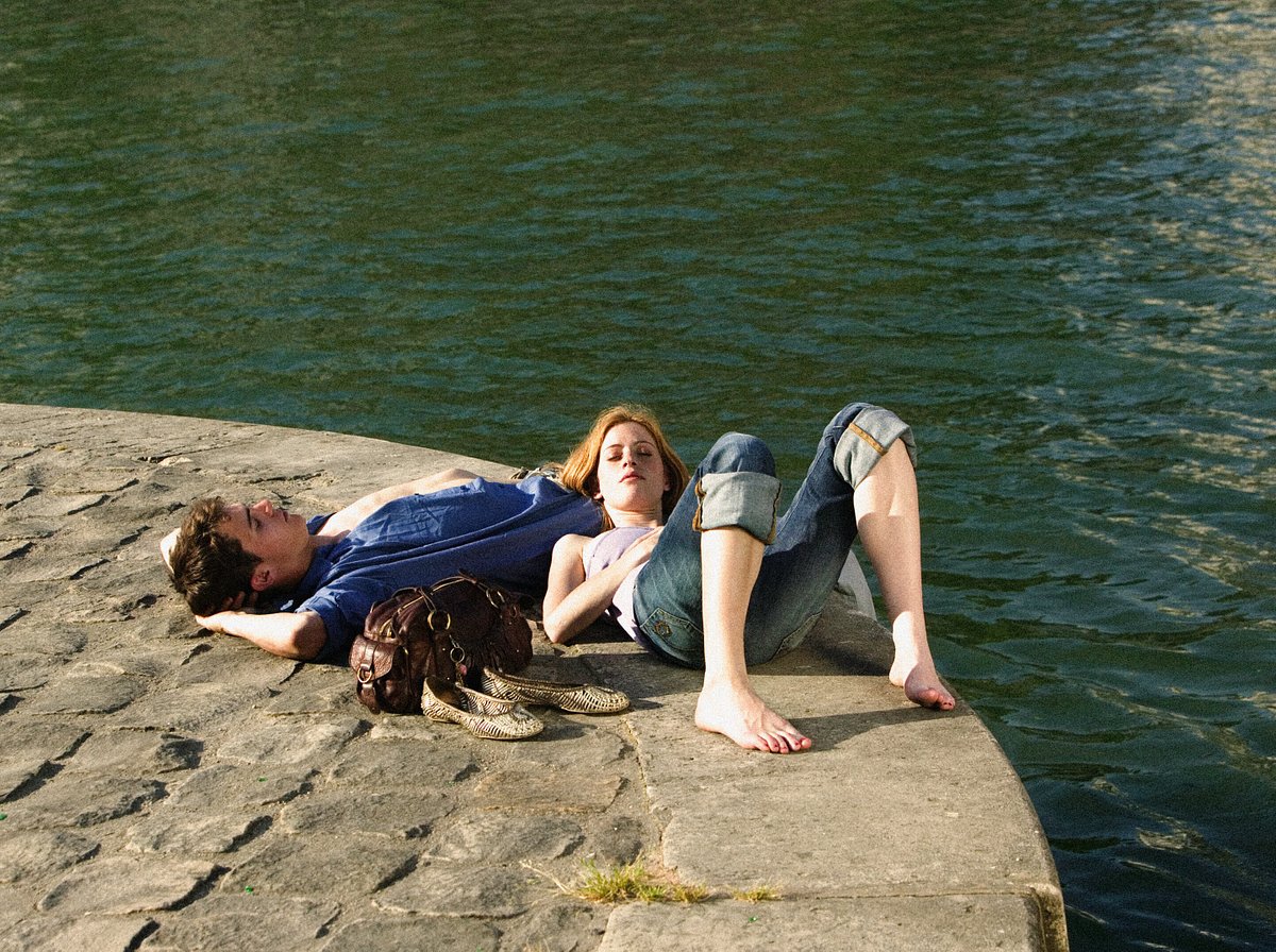 Man en vrouw liggen in de zon naast de rivier de Seine in Parijs, Frankrijk