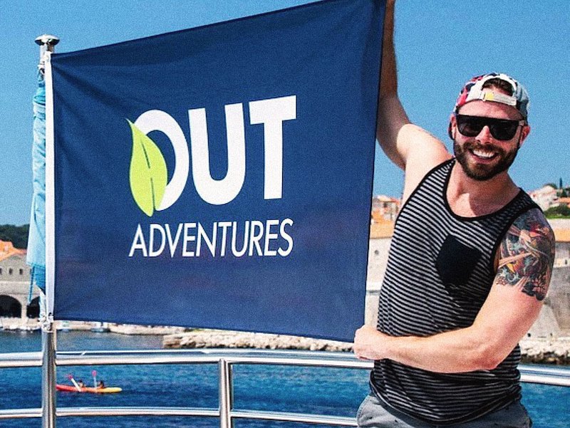 Robert Sharp of Out Adventures, holding an Out Adventures Flag
