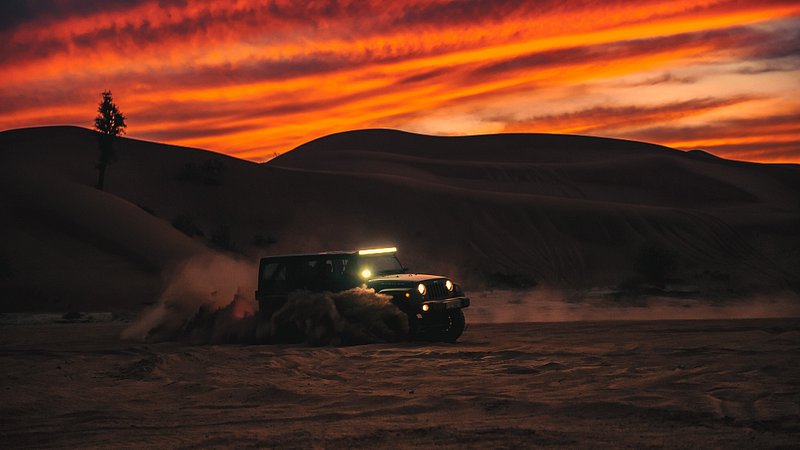 밤에 두바이의 모래 언덕을 달리는 사륜구동 자동차
