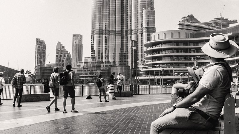 A couple sitting on a bench by the Burj Khalifa Lake with Burj Khalifa and other travelers in the background