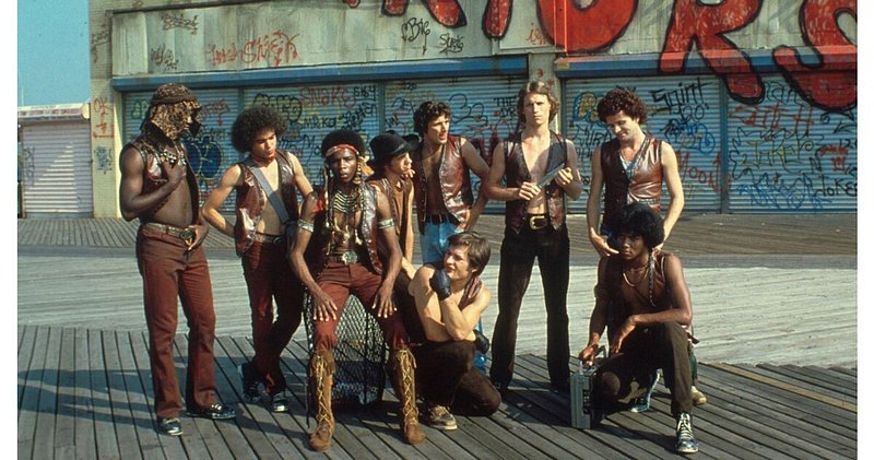 Still from The Warriors (1979) film with actors standing on the Coney Island boardwalk