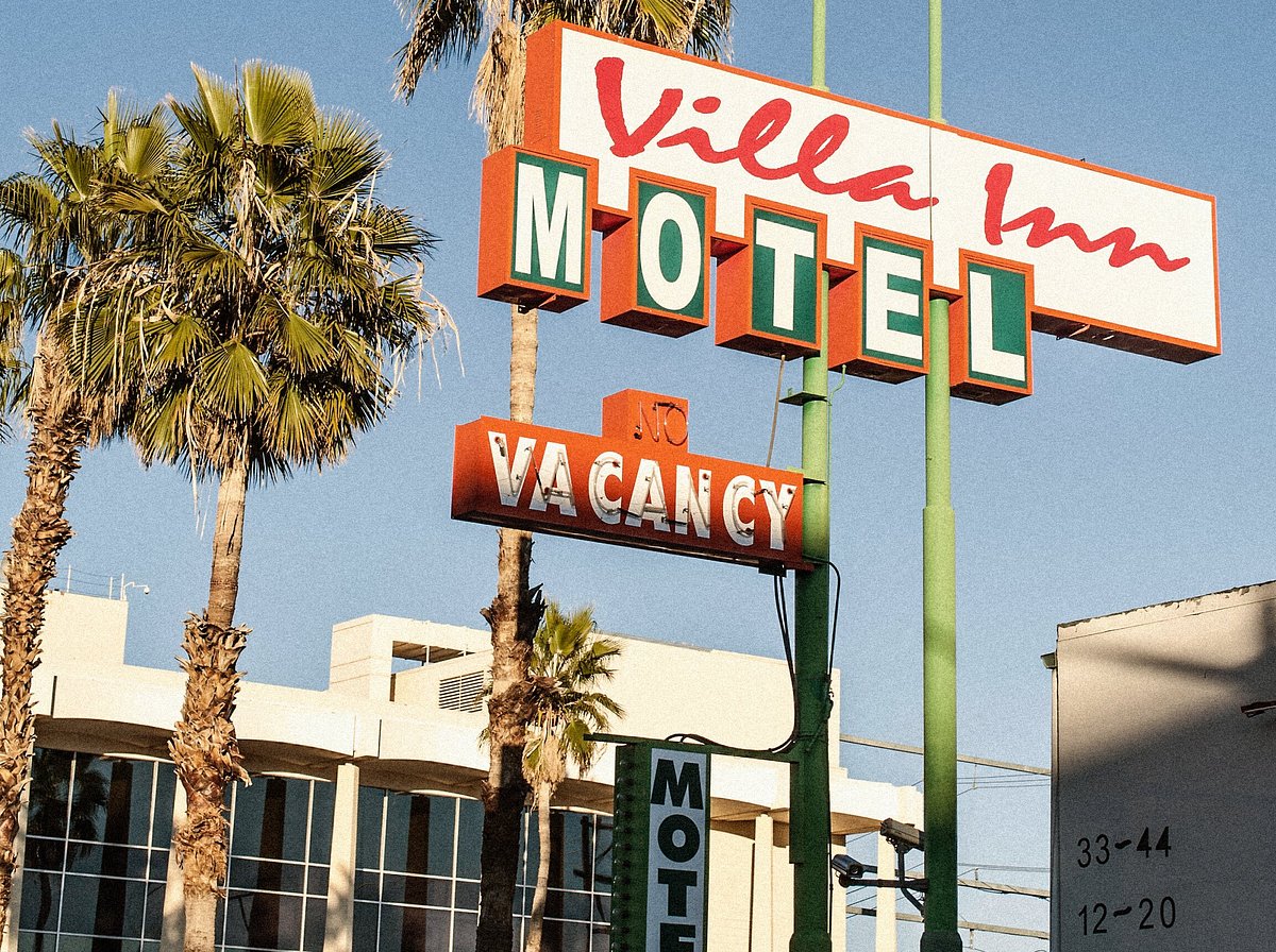 motel signs and palm trees against a blue sky