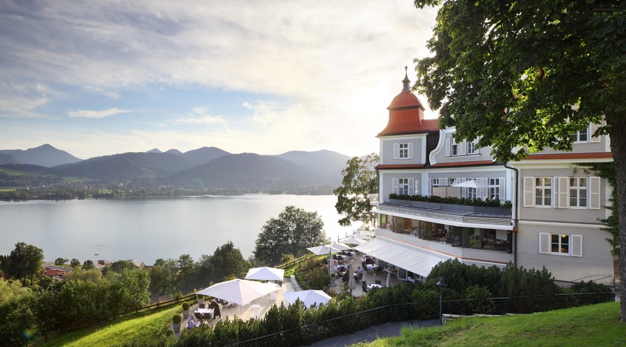 Hotel DAS TEGERNSEE mit Blick auf das Sengerschloss und den Tegernsee im Sommer