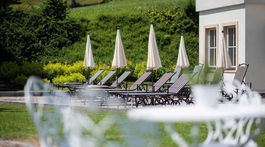 Entspannungsliegen vor dem Hallenbad beim Hotel AlpenSchlössl in der Ferienregion Wilder Kaiser. Die Tiroler BergWelt in seiner vielfallt genießen. Traumhafte Urlaubstage im Frühling, Sommer, Herbst oder Winter.