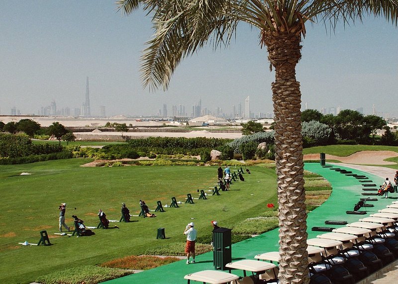 Golfers at a golf course in Dubai with view of Dubai skyline in the background