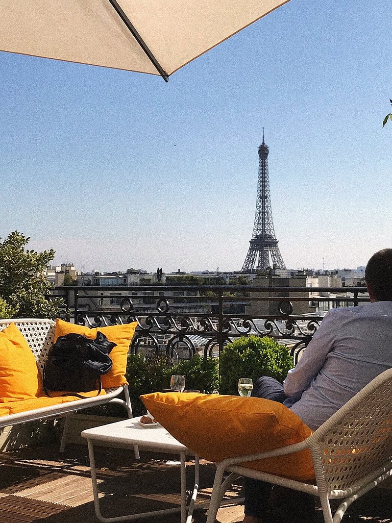 Một người đàn ông đang ngắm Tháp Eiffel từ khách sạn Hotel Raphael