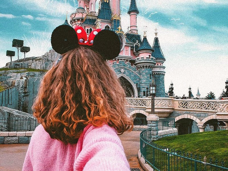 Girl wearing Mickey mouse ears in front of the Disneyland Paris Castle