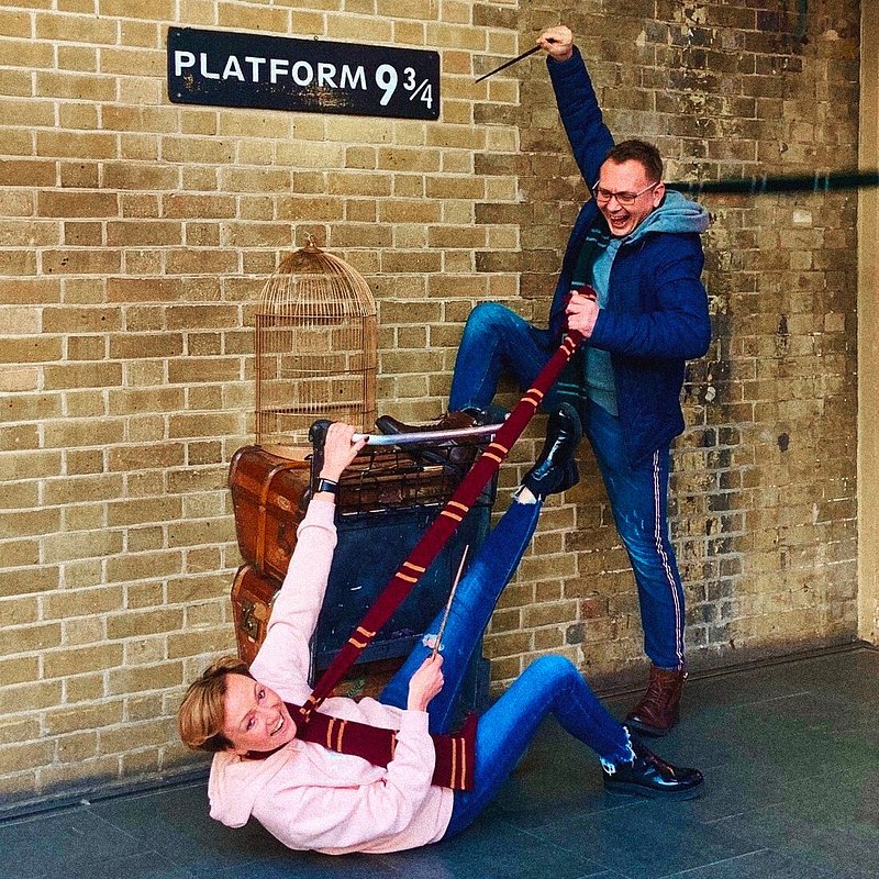 Ein Paar am Gleis 9 3/4 im Bahnhof King's Cross in Harry-Potter-Pose