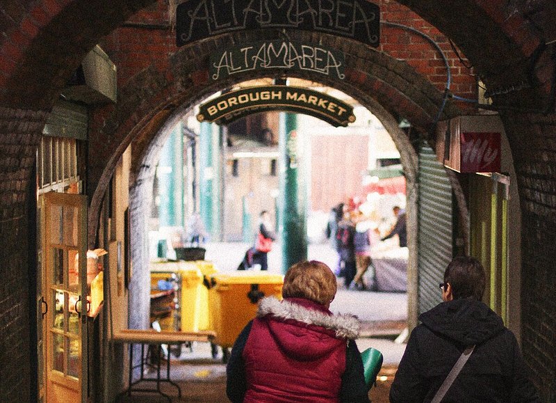 Two women walking under an archway at Borough Market in London