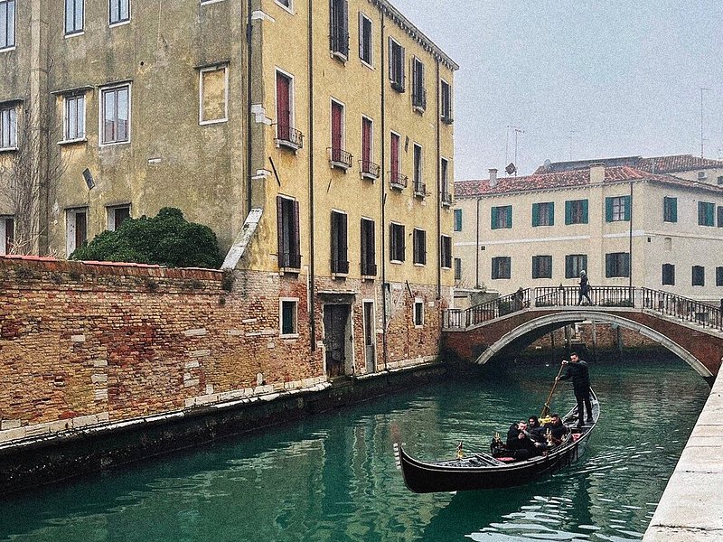 En grupp turister i en gondol i en kanal i Venedig