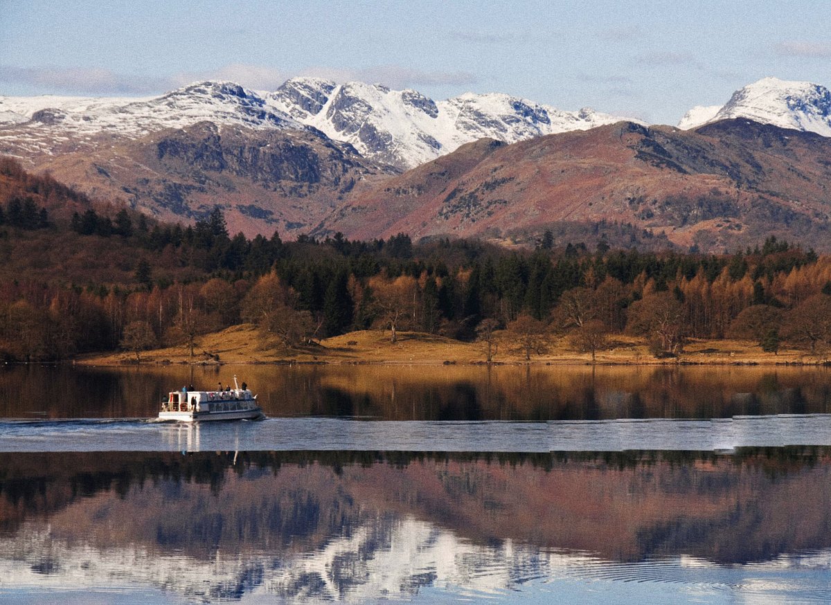 A cruise boat floats along Lake Windermere in the winter
