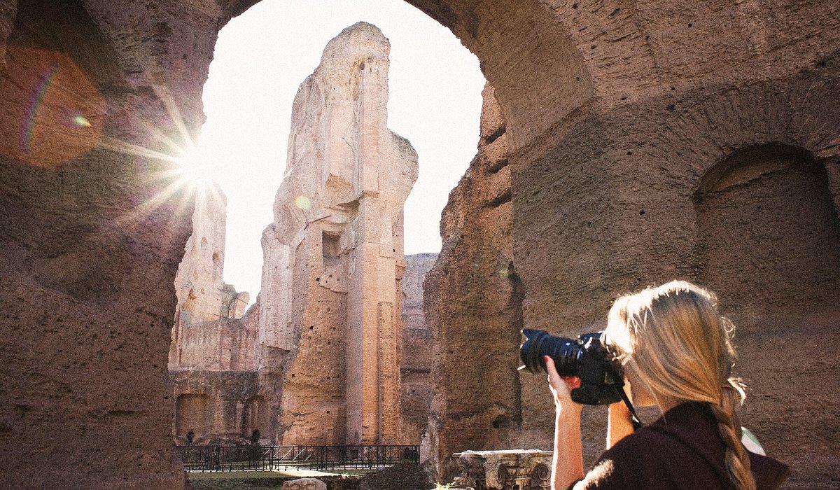 A woman taking a photo at the Baths of Caracalla in Rome, Italy