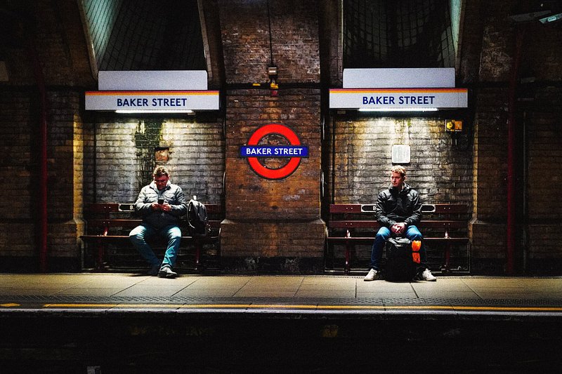 Two men waiting at Baker Street underground tube station in London at night