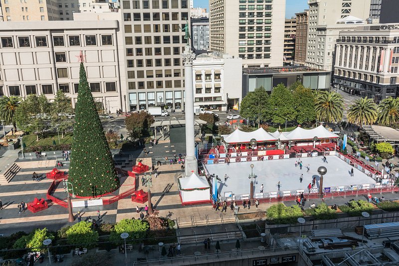 Overlooking Union Square in the daylight, with a large Christmas tree on the left and skating rink on the right
