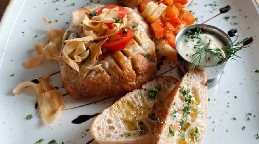 Vegan Wellington with fried root vegetables, garlic mushrooms, potatoes and a garlic sauce.