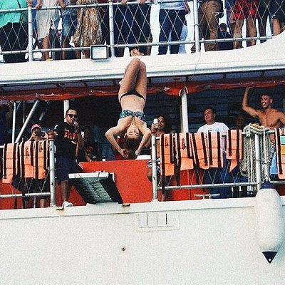 A woman jumping into the water from a dancing catamaran cruise at spring break in Cancun
