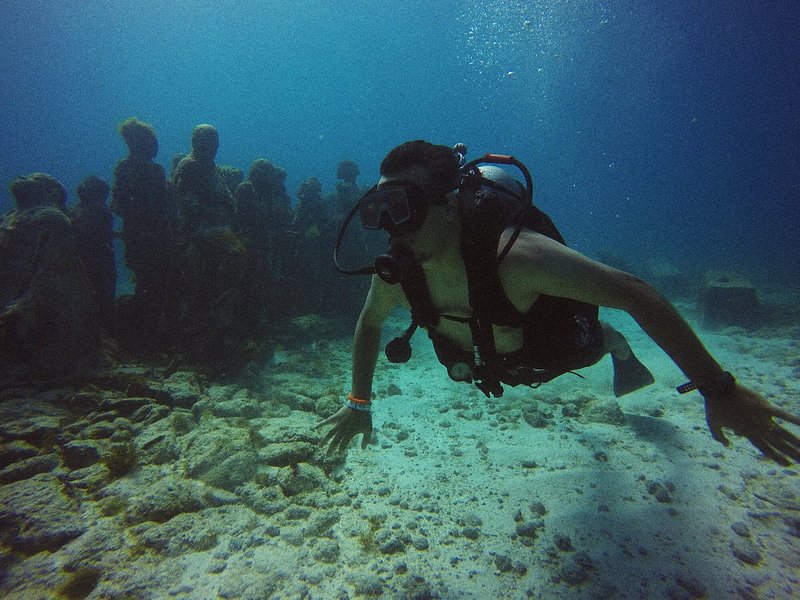 A man diving at Cancun's Underwater Museum of Art