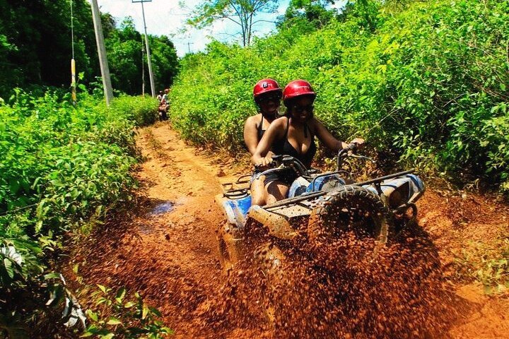 A couple riding on an ATV through the mud in Cancun Mexico