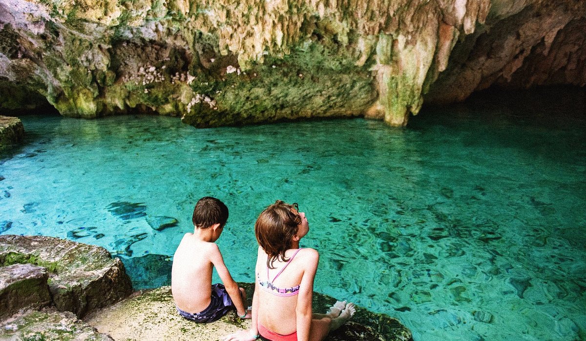 Two kids sitting in a cenote in Cancun